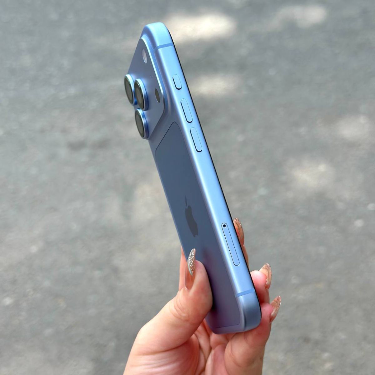 Cầm iPhone 18 Pro Max màu xanh trời tại Táo US ngoài trời nhìn từ cạnh